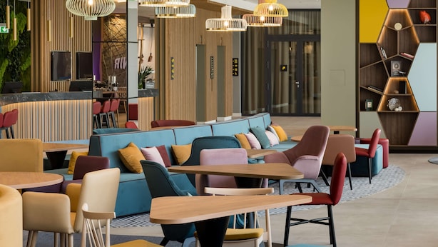 Ein moderner Lounge-Bereich mit Sitzgruppen, darunter Sofas und Tische, sowie einem dekorativen Bücherregal.