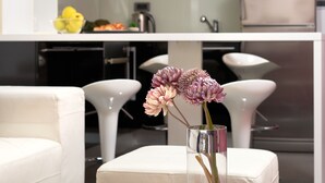 A modern kitchen with white cabinets, a white countertop, and two black pendant lights. - Sun Spalato Suite (Makarska)