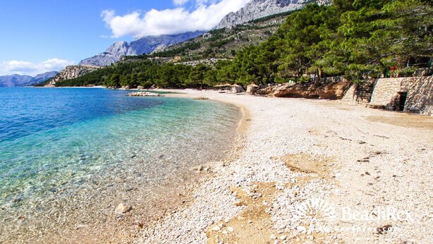 A clear beach with pebbles, a rocky shoreline, and a mountainous backdrop. - Sun Spalato Suite (Makarska)