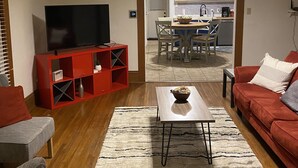 A living room with a TV, red entertainment unit, and a dining area with a table and chairs. - Cheerful Downtown 3 Bedroom home in the historic area of Columbus (Columbus)