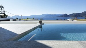 A swimming pool with a clear view of the sea and mountains in the background.