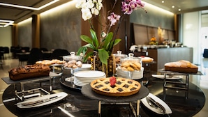 A buffet table with various desserts and a floral centerpiece. - Gold Tower Lifestyle Hotel (Naples)