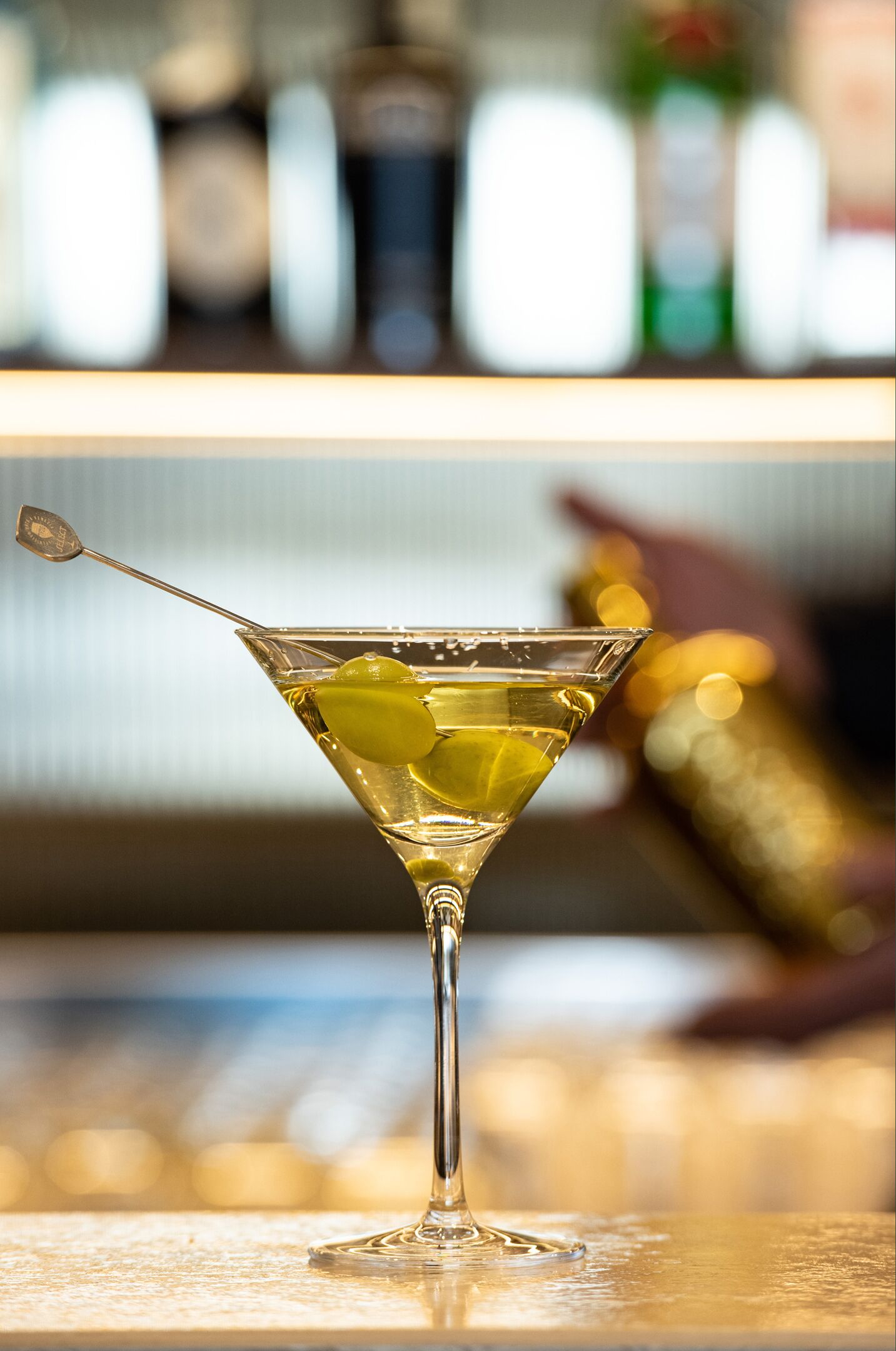 Una copa de martini con un tallo y una rodaja de limón sobre una barra.