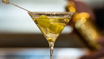 Una copa de martini con un tallo y una rodaja de limón sobre una barra.