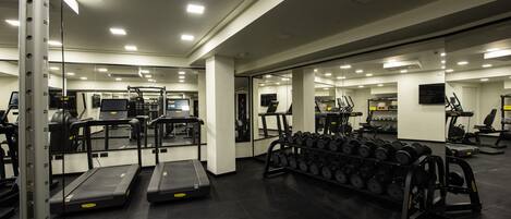 Une salle de sport équipée de tapis de course, d’appareils de musculation et d’un porte-haltères.