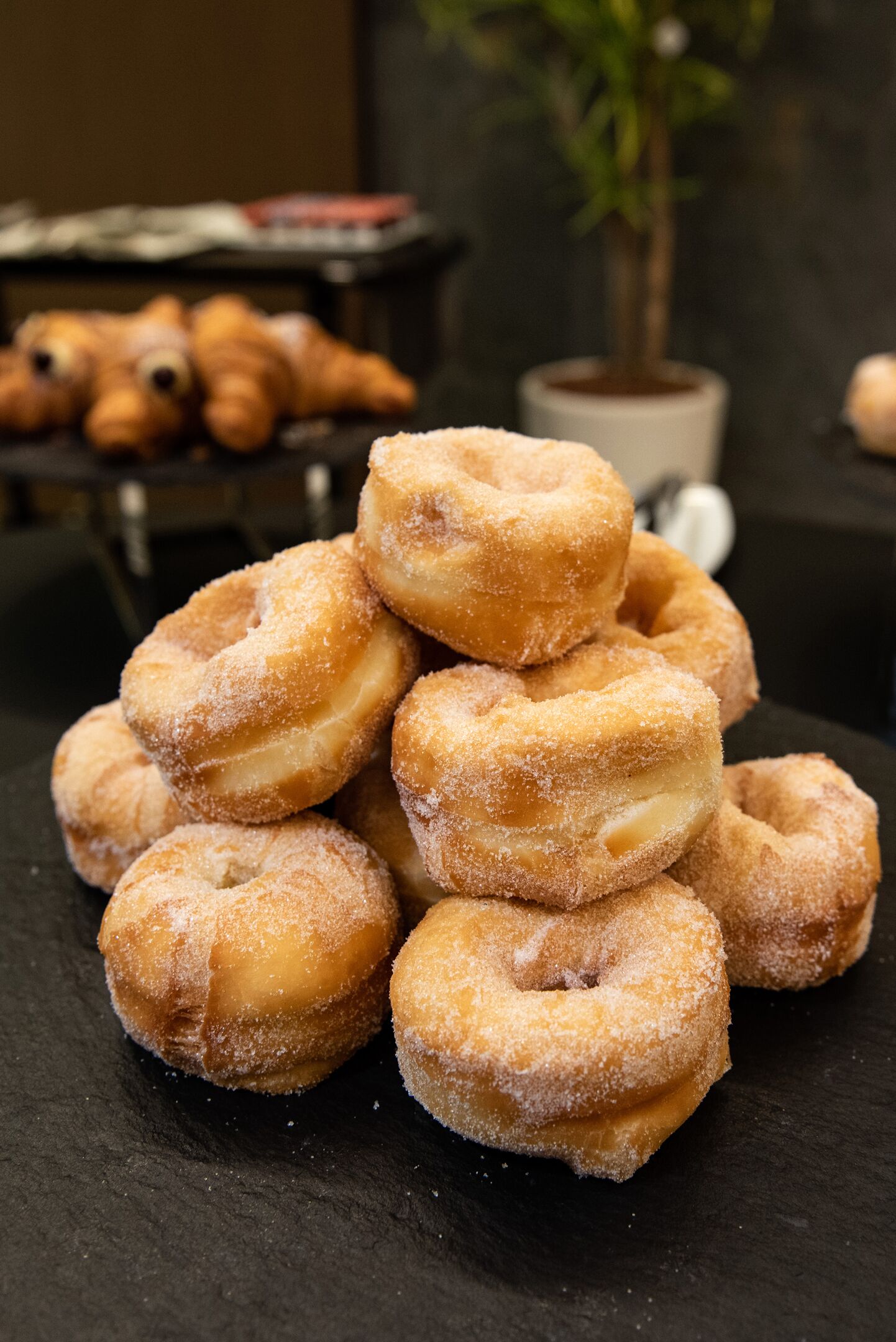 Une pile de beignets enrobés de sucre sur une surface sombre.