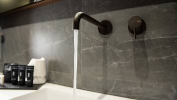 Un bagno con un rubinetto moderno e una parete in marmo.