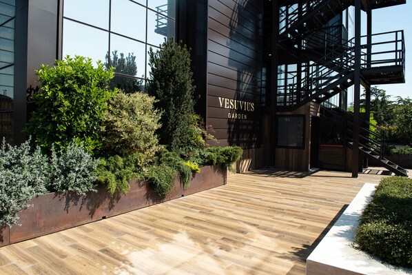 A modern building with a wooden floor, a metal staircase, and a sign that reads "VESUVIUS GARDEN".