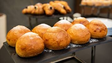 A display of round, golden-brown pastries dusted with powdered sugar, arranged on a black tray.