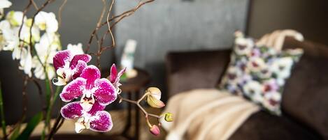 A bedroom with a bed, a nightstand, and an orchid plant.