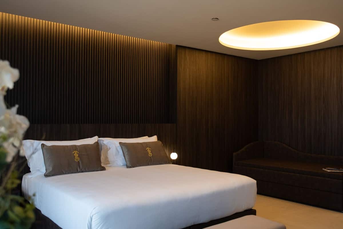 A modern bedroom with a large bed, a bedside table, and a bench.