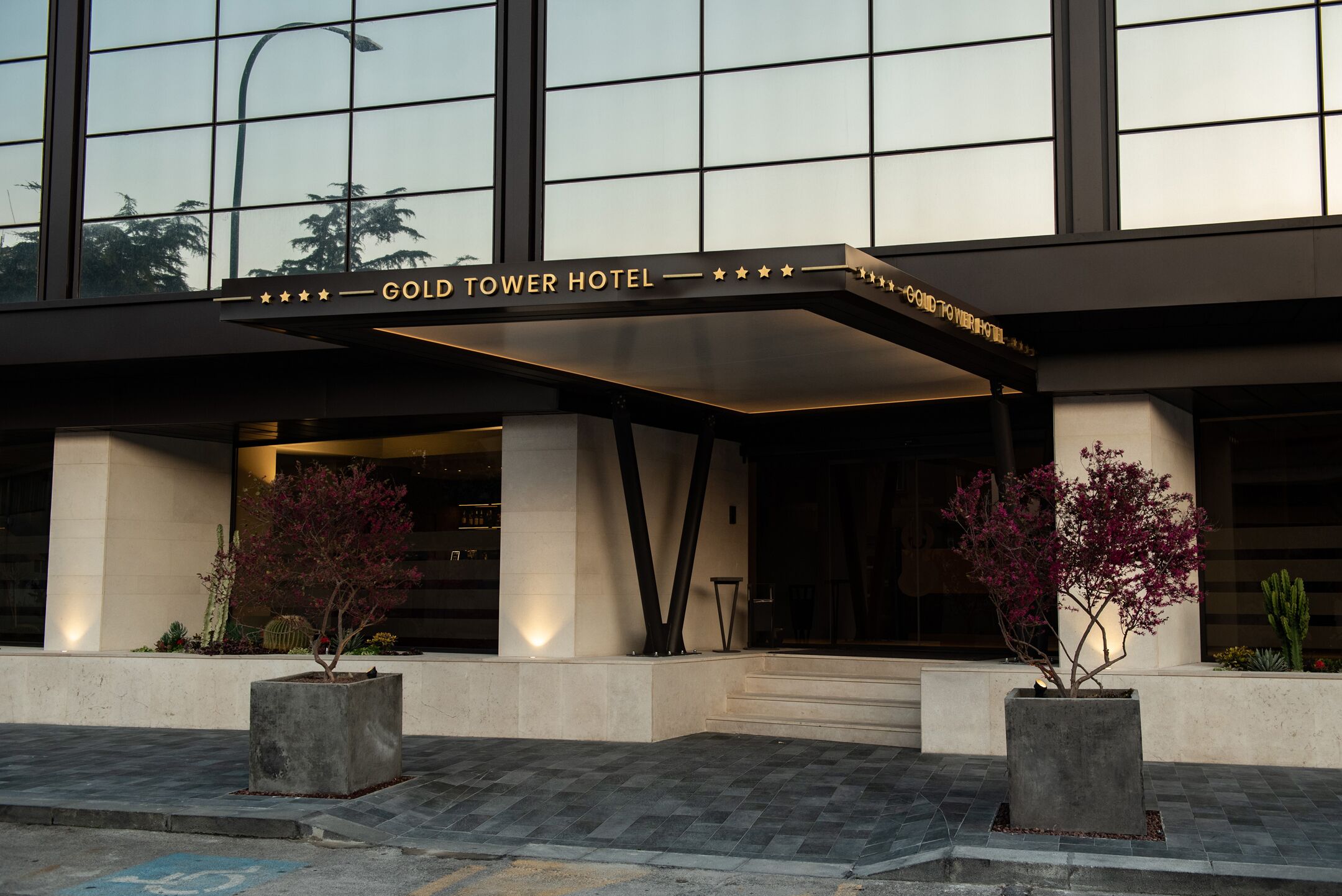 Het exterieur van Hotel Gold Tower met een modern ontwerp, met een opvallende entree en een goed zicht op de gevel van het gebouw.
