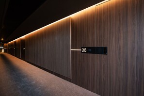 A hallway with a wooden wall and a sign indicating room number 206. - Gold Tower Lifestyle Hotel (Naples)