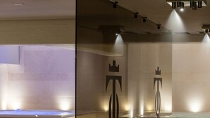 A modern bathroom with a glass partition, a wooden chair, and a towel rack. - Gold Tower Lifestyle Hotel (Naples)
