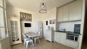 Uma cozinha compacta com mesa, cadeiras, geladeira, micro-ondas e pia.
