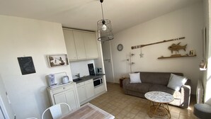 Um espaço compacto com cozinha compacta, área de refeições e sala de estar com sofá e mesa redonda pequena.