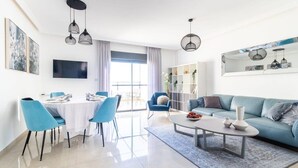 Un salon moderne comprenant un coin repas, un canapé, une table basse et un téléviseur fixé au mur.
