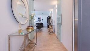 A modern hallway with a glass table, a large mirror, and a wooden floor.