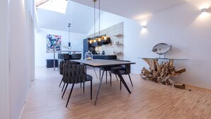 A modern dining area with a wooden floor, a glass-top table, and black chairs.
