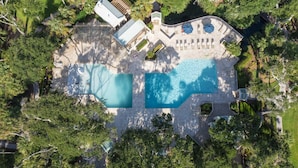 Vue aérienne d’une propriété dotée de deux piscines, d’un patio couvert et d’une végétation luxuriante.