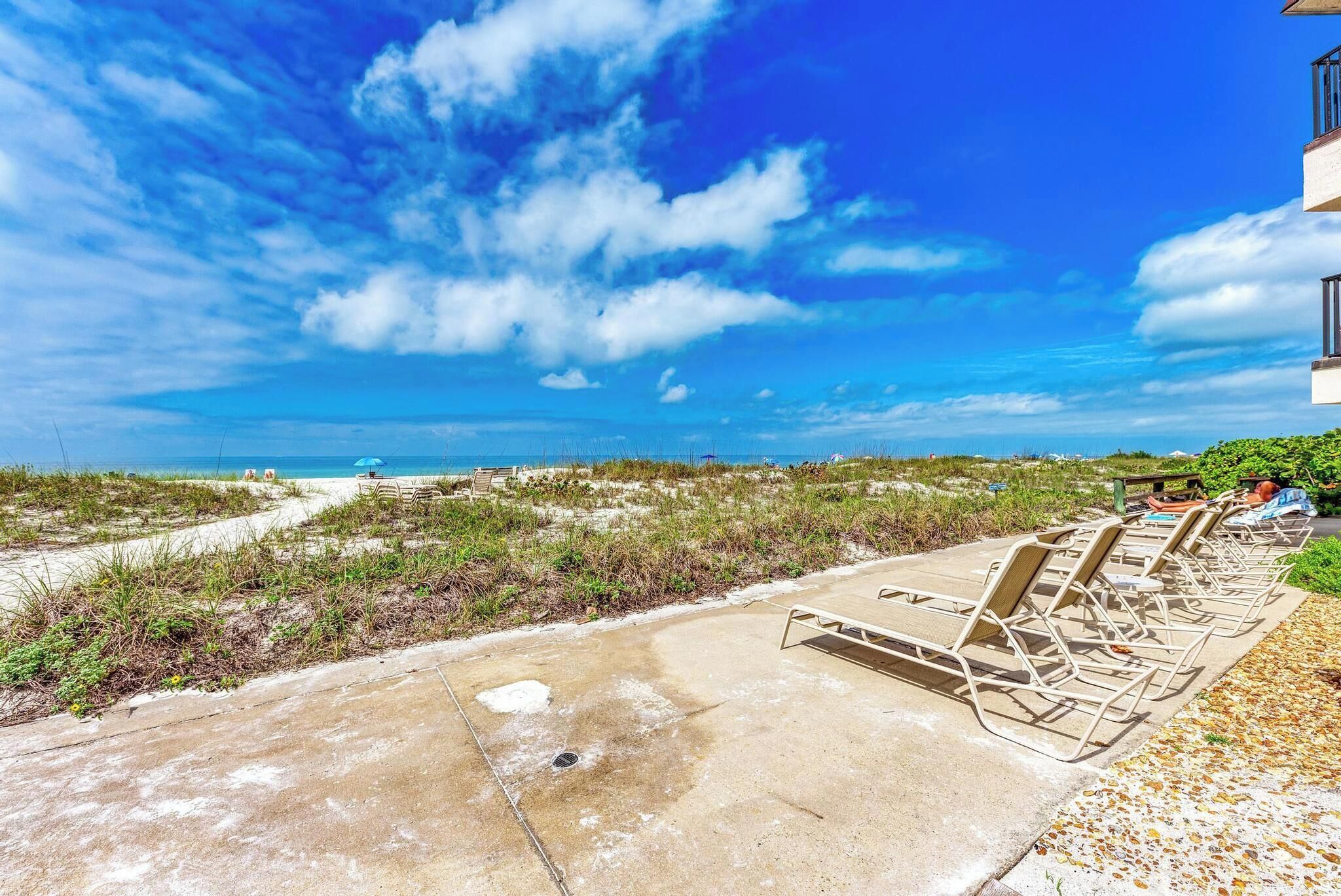 A beachside view with lounge chairs and a clear sky.