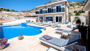 Una villa moderna con piscina, zona de estar exterior y vistas del paisaje circundante.