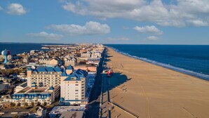 Eine Küstenstadt mit einem Hotel direkt am Strand, einem Steg und einem klaren Himmel.