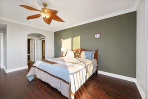 Un dormitorio con una cama, un ventilador de techo y una puerta que da a otra habitación.