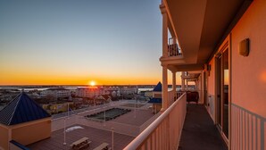 Ein Balkon mit Blick auf den Sonnenuntergang über einer Küstenstadt.