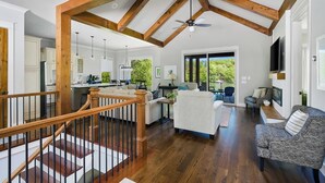 Amplia sala de estar con techo de madera, una escalera y vistas al exterior.