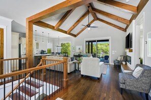 A spacious living area with a wooden ceiling, a staircase, and a view of the outdoors.