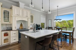 A kitchen with a large island, bar stools, and a view of a lake.