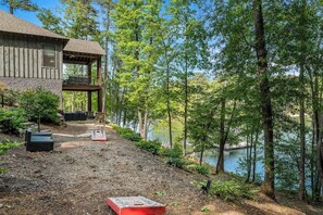 A cabin with a deck overlooking a lake, surrounded by trees.