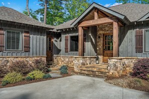 A two-story house with a stone foundation, wooden siding, and a stone staircase leading to the front door.