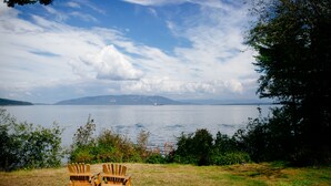 Two wooden Adirondack chairs facing a lake with a distant boat and mountains. - Orcas Island, Peapod Cottages with Barn #290B (Orcas Island)