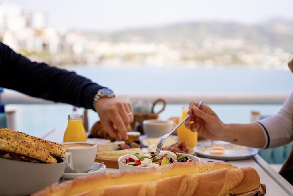 Uma mesa de jantar com itens de café da manhã, incluindo croissants, uma salada e uma xícara de café.