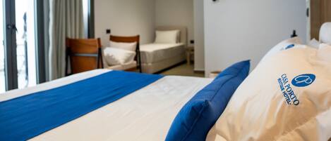 A hotel room with a bed, a chair, a desk, and a window with curtains.