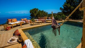 A poolside area with lounge chairs and a hammock, overlooking a clear blue sea. - VILLA HOLIDAY RENTAL WITH PRIVATE POOL BY THE SEA, CEFALù SICILY ITALY  (Sicilia cefalu')