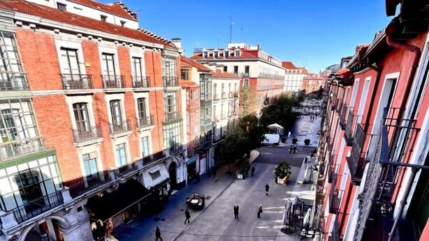 A street view from a balcony overlooking a pedestrian area with buildings, a clear sky, and a few people walking. - Espacios Blanco Plaza Mayor LUX: two rooms, 5 beds, balconies with views of the Plaza Mayor itself! (Valladolid)