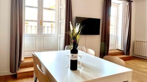 A dining area with a table, chairs, a bottle of wine, and a glass. - Espacios Blanco Plaza Mayor LUX: two rooms, 5 beds, balconies with views of the Plaza Mayor itself! (Valladolid)