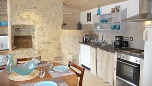 A kitchen with a stone wall, wooden ceiling, and a dining area with a table set for four.