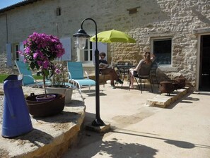 Relax in the serene outdoor patio area with a stone wall, potted plant, and comfortable seating.