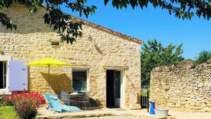 A stone building with a patio, outdoor seating, and a yellow umbrella.