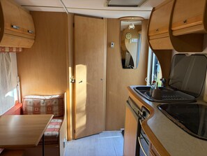 Ein kompaktes Wohnmobil-Interieur mit einer Küchenzeile, einer kleinen Essecke und einer Schlafkoje.