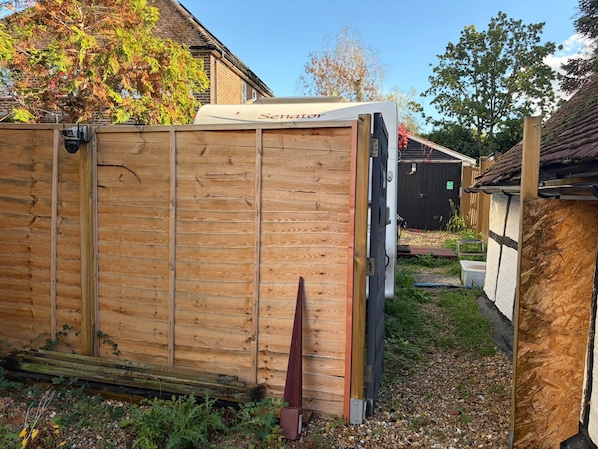 A wooden shed with a 'Senator' sign, a black door, and a small garden area with gravel and plants. - Unique Stay  Private & entire place near Gatwick Airport (Crawley)