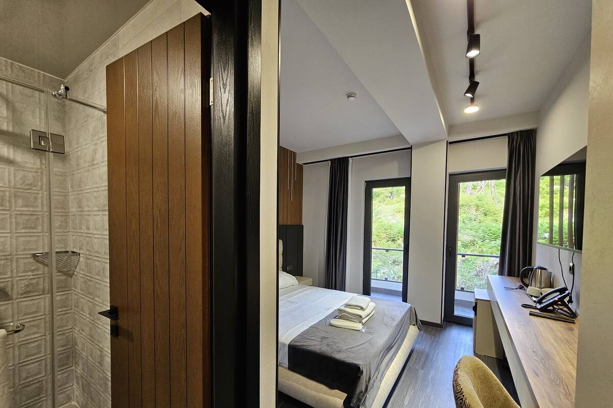 Quarto de hotel moderno com uma cama grande, uma escrivaninha e vista para o exterior.