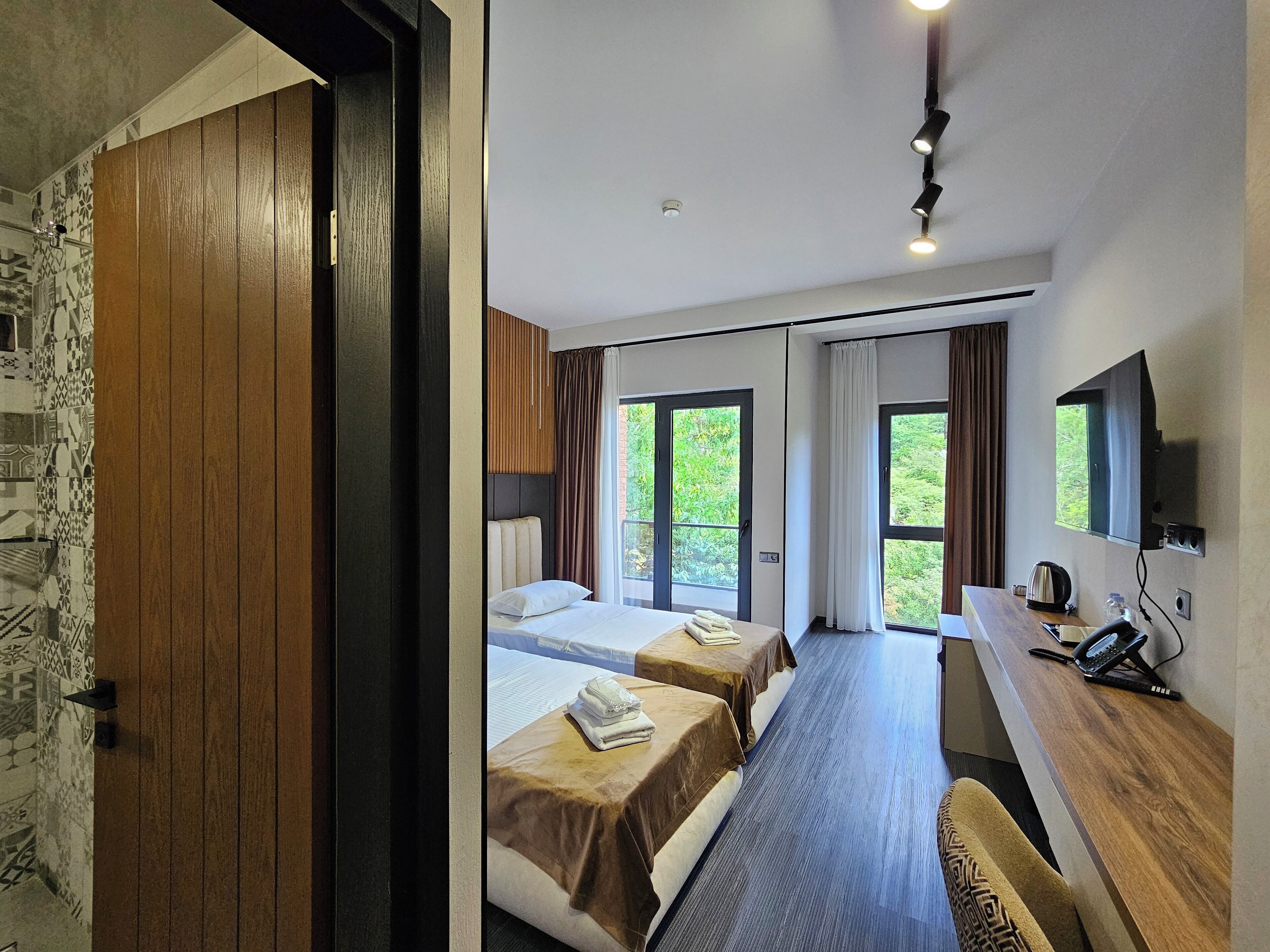Habitación de hotel con dos camas, un escritorio, un televisor y vistas a zonas verdes.