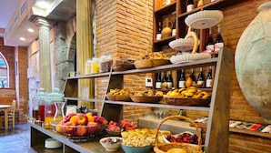 Un bufé con diversos alimentos, entre ellos frutas, pastelería y bebidas.