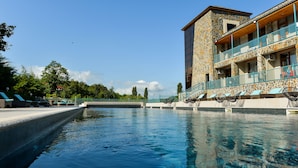 Una piscina con sillas de descanso y un edificio de piedra con balcones.