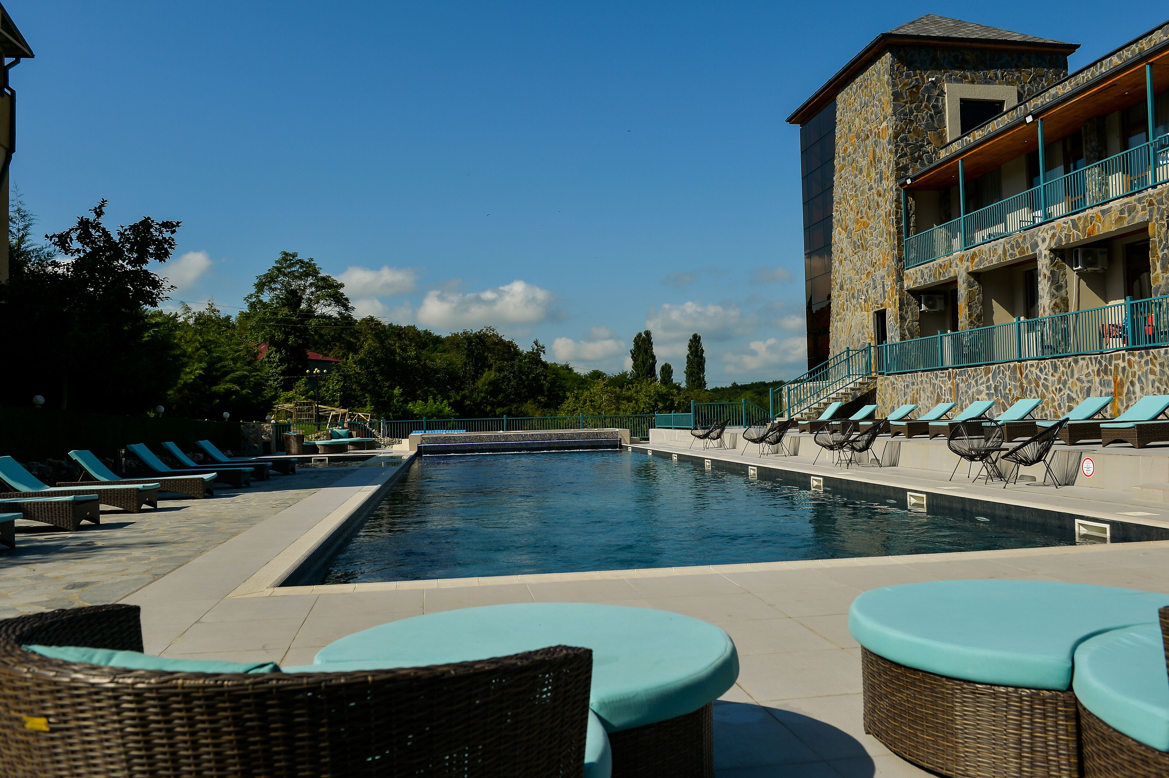 A pool area with lounge chairs and a stone building with balconies.
